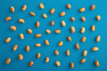 Baked soybeans pattern on a blue background. Nuts creative layout. Top view