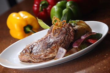 T-bone steak grilled beef with red and green peppers and baked potato.
