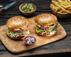 Hamburgers and French fries on the wooden tray.