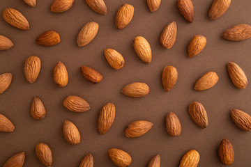 Almonds pattern on a brown background viewed from above. Nuts creative layout. Top view