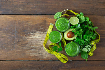 Green detox smoothie with measuring tape on wooden background detox juices concept