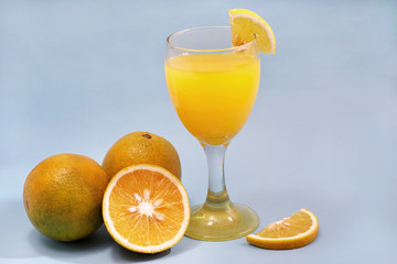 a glass of sweet orange juice and orange slices isolated on blue