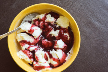 close up. a vanilla ice cream topped with fresh red berries. Delicious summer dessert on a yellow plate. Delicacy. Goodbye diet. Junk food.