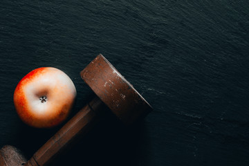Old rusty iron dumbbell and red apple on black table as background with copy space - Heavy fitness weight for bodybuilding used in gyms - Concept image for health care and sports