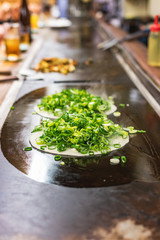 Okonomiyaki, Japanese pancake in the making. Tasty traditional dish from Hiroshima prefecture, Japan.