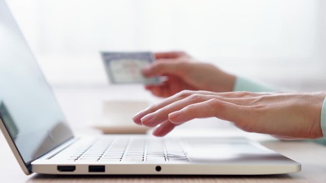Woman freelancer typing on laptop at home-office. Blurred female hand holding social security number on background. Businesswoman filling out tax return form online at work. Dolly shot