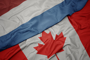 waving colorful flag of canada and national flag of luxembourg.