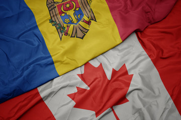 waving colorful flag of canada and national flag of moldova.