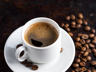 White espresso coffee Cup and coffee beans on rusty dark background