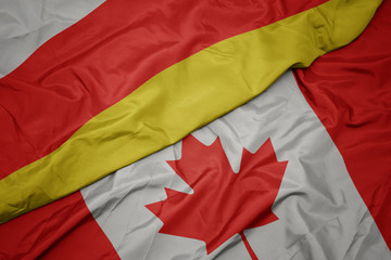 waving colorful flag of canada and national flag of south ossetia.