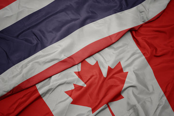 waving colorful flag of canada and national flag of thailand.