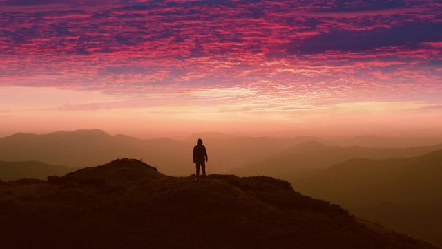 The man standing on a mountain top against the beautiful sunset