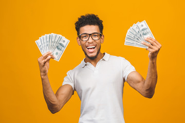 Winner! Young rich african american man in casual t-shirt holding money dollar bills with surprise...