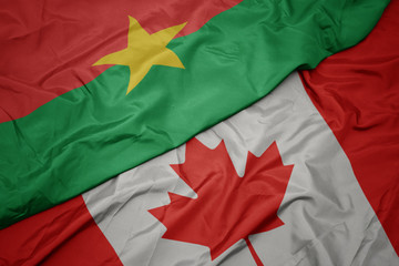 waving colorful flag of canada and national flag of burkina faso.