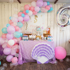 Mermaid Candy Bar. Delicious sweet buffet with cake. A beautiful buttercream cake decorated with mermaid tails. Design of balloons. Children Birthday party.