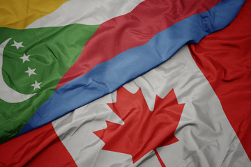 waving colorful flag of canada and national flag of comoros.