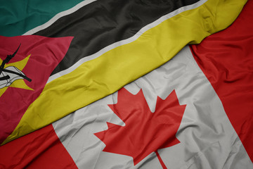 waving colorful flag of canada and national flag of mozambique.