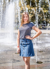 portrait of young attractive caucasian woman in casual clothes near fountain in the urban park