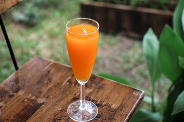 fresh orange juice on chair wooden and grass green background