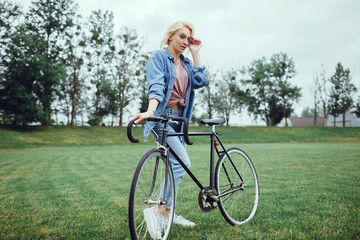 Pretty woman using cycling on the street,outdoor fashion portrait,hipster style ,sunglasses, sneakers,outdoor woman portrait on bike cycle,happy face,close up.spring, sunglasses fashion,cute,emotional