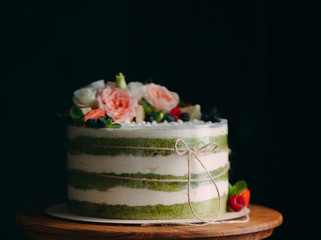Cake is decorated with flowers on a dark background.