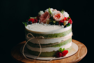 Cake is decorated with flowers on a dark background.