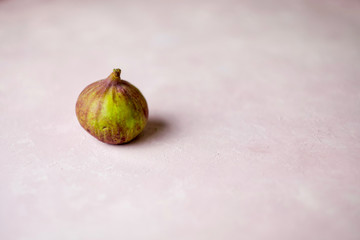 whole fig on a light pink marbled background with copy space. Selected focus