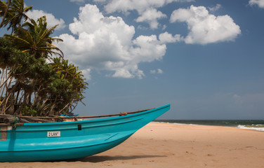 Fototapeta na wymiar A beach in Sri Lanka with a fishing boat on the shoreline with coconut trees on the background