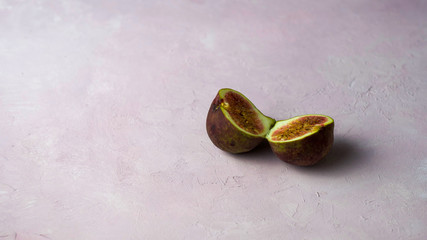 Arrangement of fresh cut figs with some flowers on a light pink marbled background with copy space. Selected focus