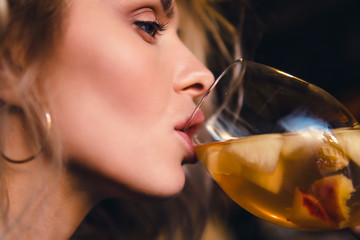 Beautiful girl in drinks Aperol Spritz wine from a glass in a restaurant, a cafe, has a good...