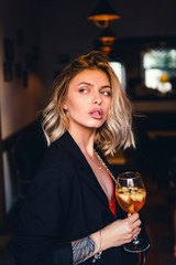 Beautiful girl in drinks Aperol Spritz wine from a glass in a restaurant, a cafe, has a good weekend, a stylish fashionable woman, a brunette young, emotional, outdoor close up hipster portrait