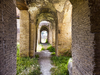 Fototapeta na wymiar Corridors of the ancient Roman buildings in the archaeological excavations of Ostia Antica, arches and ceilings with stuccoes and well preserved decorations