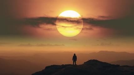 The man standing on a mountain top on the bright sunrise background. time lapse