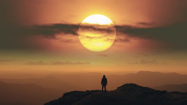 The man standing on a mountain top on the bright sunrise background. time lapse