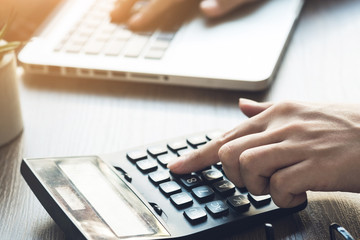 Business accountant man is using the calculator to calculate the income while typing to note on...