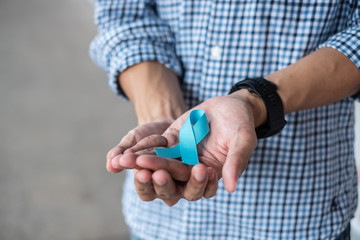 November Prostate Cancer Awareness month, Man in blue shirt with hand holding Blue Ribbon for...