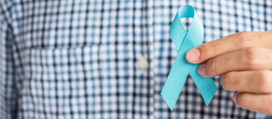 November Prostate Cancer Awareness month, Man in blue shirt with hand holding Blue Ribbon for...