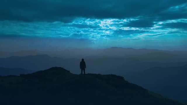The man standing on a mountain top on a moolight background