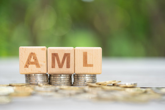 Money laundering concept, wooden word block "AML" on plie of coins.