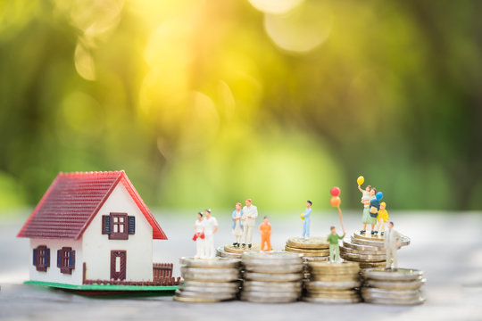 Miniature people: family standing on coins stacks with  house model on the top stack.  concepts. Concept for property ladder, mortgage,real estate investment, money, love and Valentine's day.