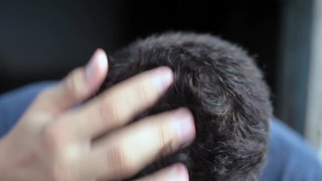 Hairs of caucasian white teenager boy itching them isolated on black background wearing a blue colored t-shirt.