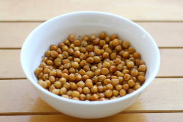 Bowl of roasted crispy chickpeas on wooden table. Selective focus.