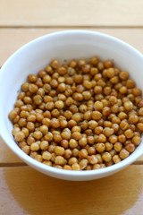 Bowl of roasted crispy chickpeas on wooden table. Selective focus.