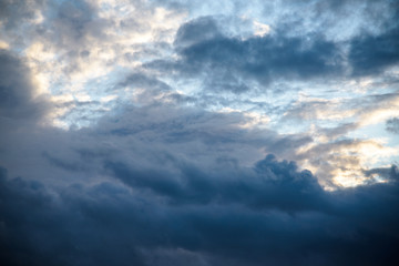 CLOSE UP: Dark grey stormy clouds gather above Lake Maggiore on a calm summer evening. Dramatic shot of clouds covering up the colorful sunlit morning sky. Orange hued evening sky and stormy clouds.