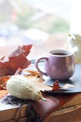  Cup of tea on the background of the window, behind which rain, pumpkins, a warm scarf, leaves, autumn season, the concept of home comfort