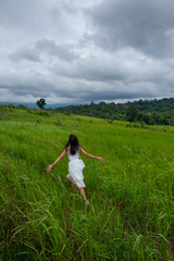 Girl with white dress running in a green field,enjoying in the sunny summer day