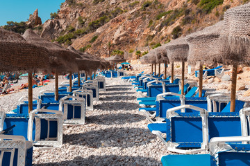  Beach Umbrella and  deckchairs at picturesque Beach  lagoon  with turquoise  water in Javea , Alicante, Spain.