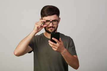 A young guy looks into the phone with his eyes narrowed. sees nothing
