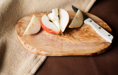 Fresh Forelle pear cut up with a paring knife on wooden cutting board