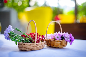 Fototapeta na wymiar Small flower bouquet in baskets on white table